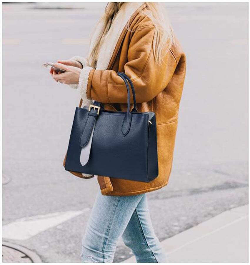 A woman carrying a blue leather handbag