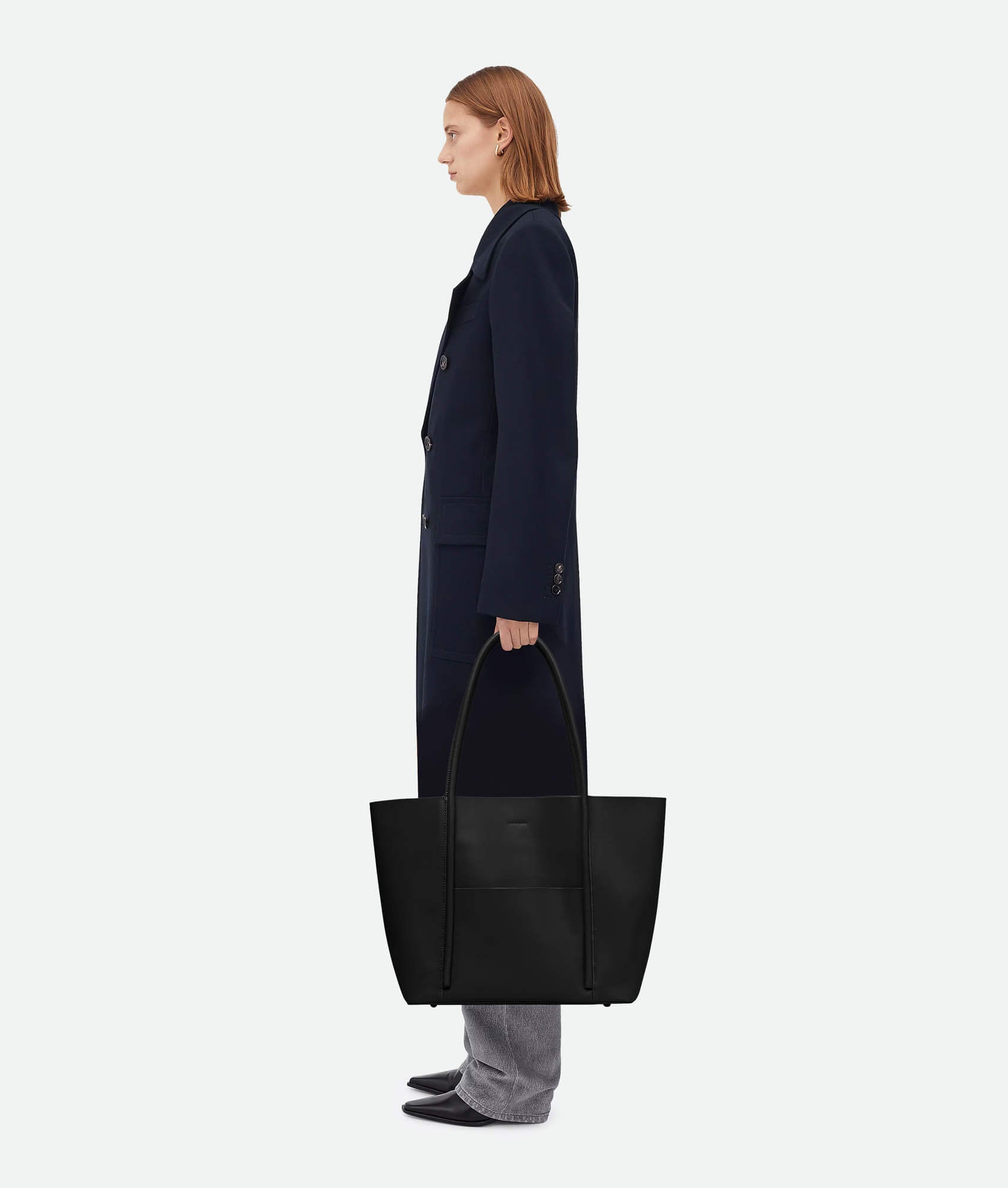 Model carrying a Black leather tote bag