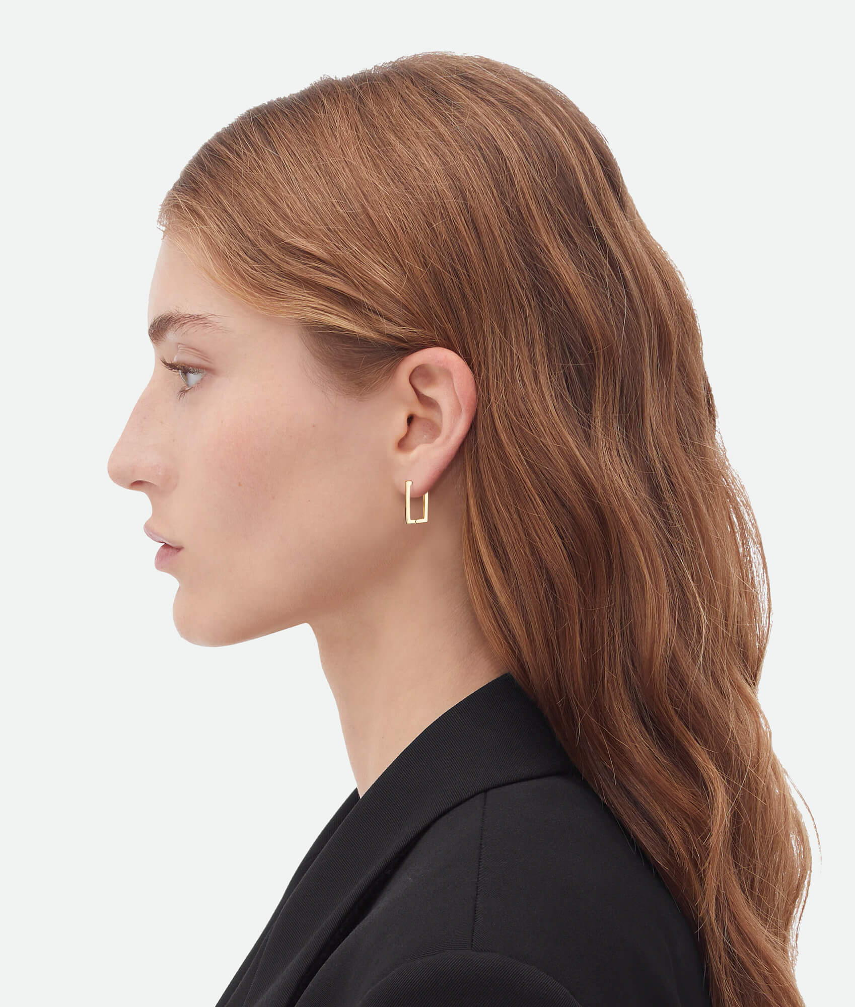 Model wearing gold block hoop earrings