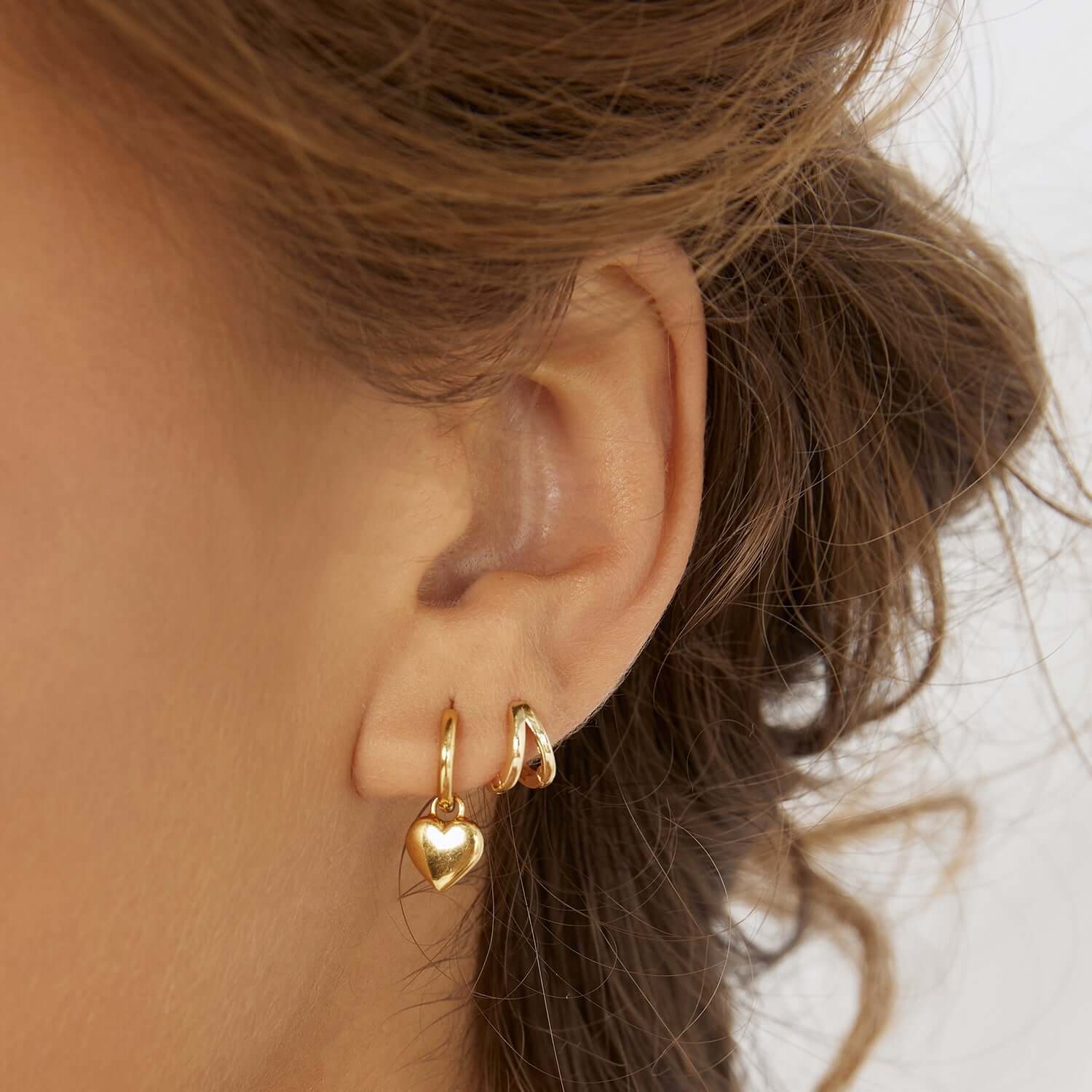 A woman showing her gold stack earrings