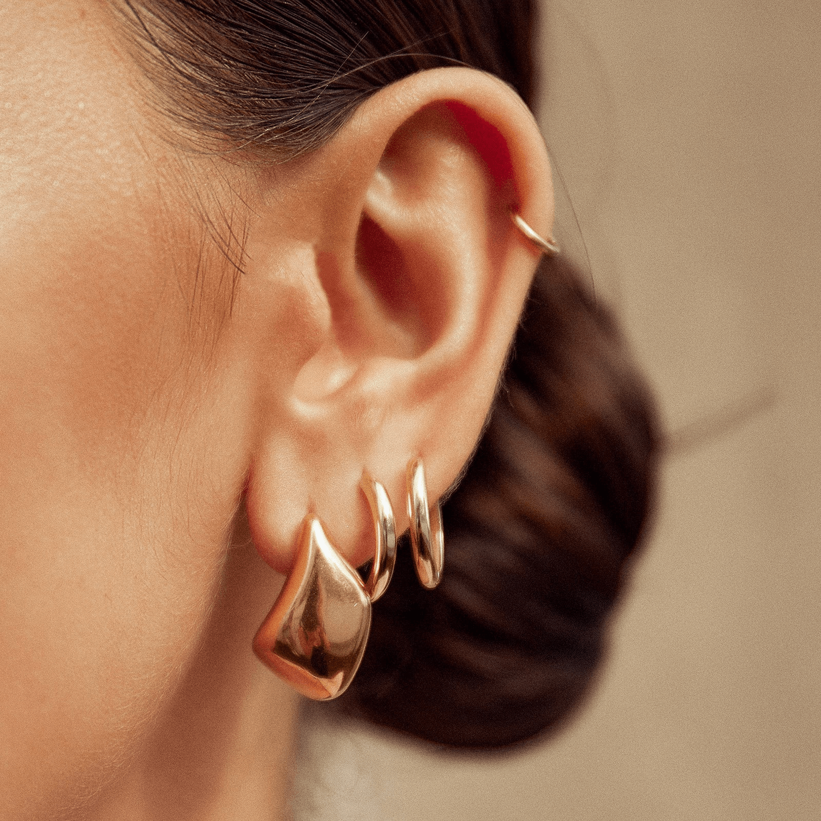 a woman showing her gold stack earrings